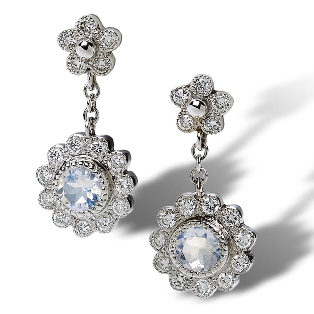 Floral motif daisy earrings in antiquing with diamonds and moonstone dangle from a budding petite daisy